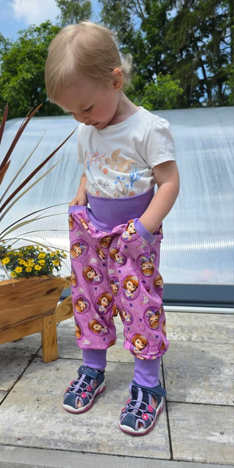 Dětské fialové tepláčky s motivem princezen, pohodlné a hravé, ideální pro každodenní nošení.