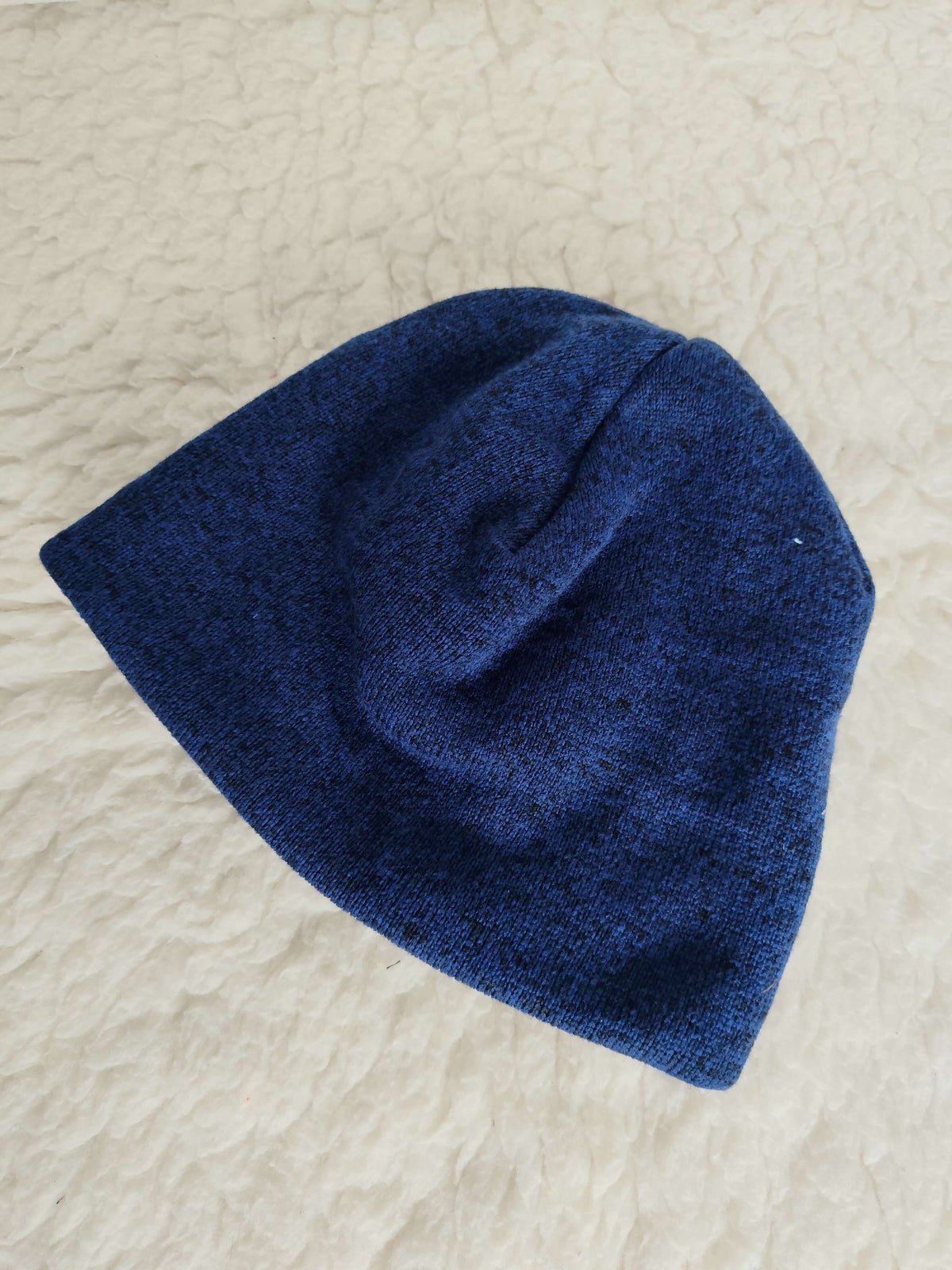 Tmavě modrá melírovaná čepice ze svetroviny je skvělým doplňkem pro chladné dny. Stylový design se snadno kombinuje s každodenním oblečením.