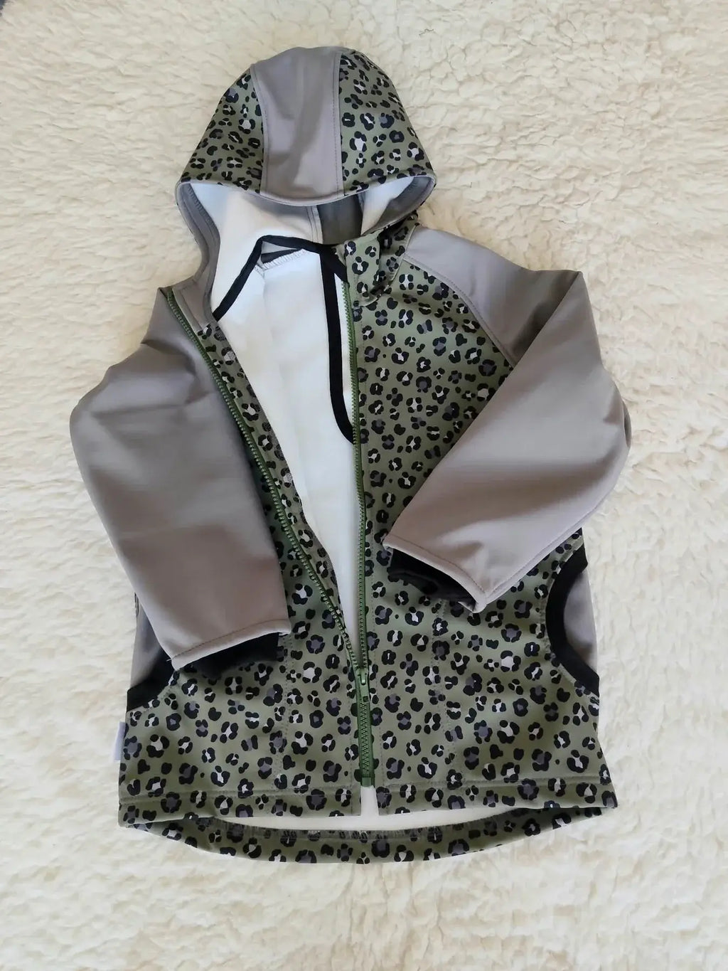 Dětská softshellová bunda s leopardím vzorem nabízí jedinečný design v khaki a šedé. Ideální pro hry venku a každodenní dobrodružství!