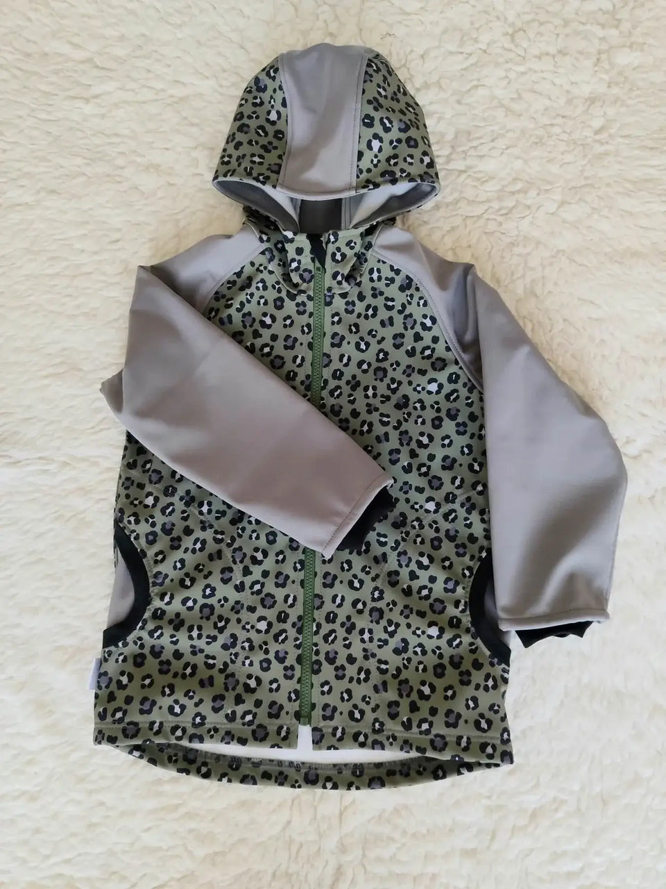 Dětská softshellová bunda s leopardím vzorem nabízí jedinečný design v khaki a šedé. Ideální pro hry venku a každodenní dobrodružství!